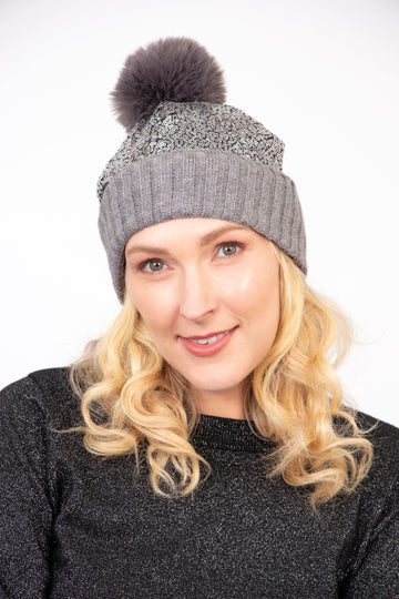 model wearing a grey hat with a pom pom and silver sequin