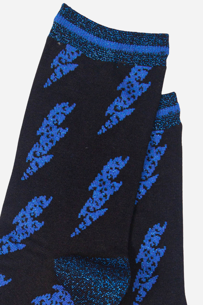 close up of the blue glitter lightning bolt pattern on the black bamboo socks