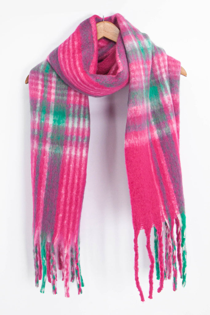 fuchsia pink and green tartan scarf draped around a coat hanger, showing how it would look when worn