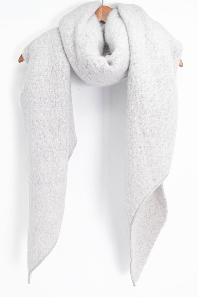 asymmetric light grey winter scarf draped around a coat hanger