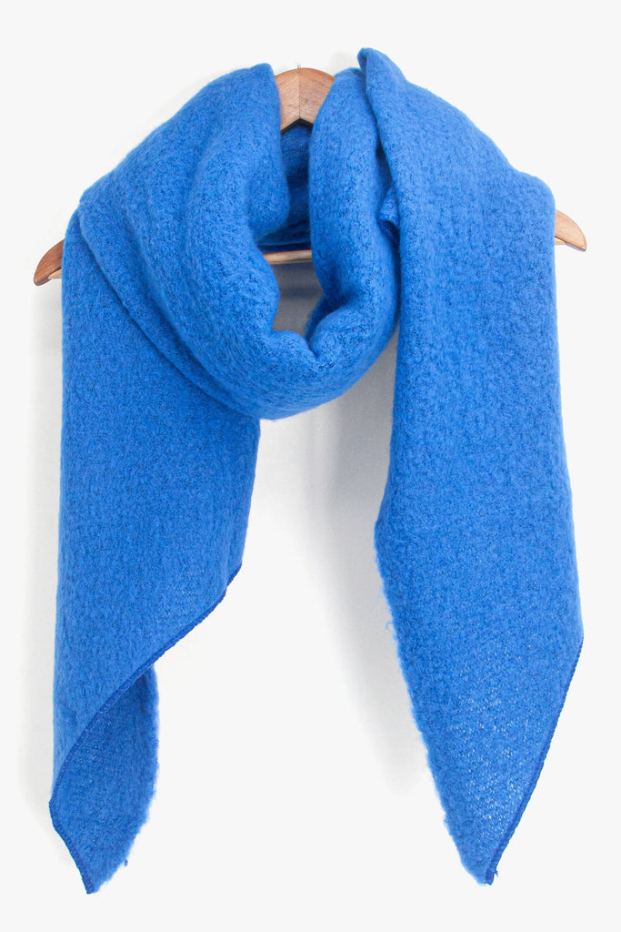 asymmetric royal blue winter scarf draped around a coat hanger
