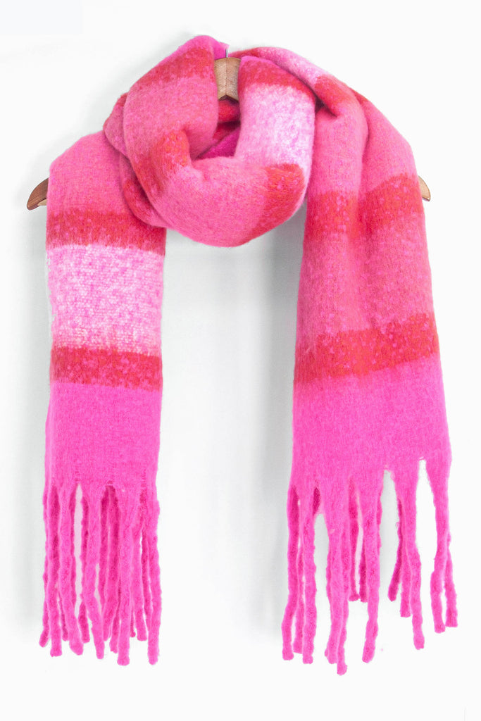 showing the pink colour block striped winter scarf draped around a coat hanger