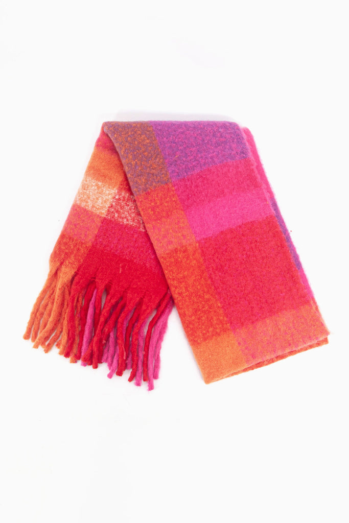 showing the scarf folded while laying flat, the multi colour  square block pattern is highlighted. there are fuchsia pink, orange and purple tones visible in the design.