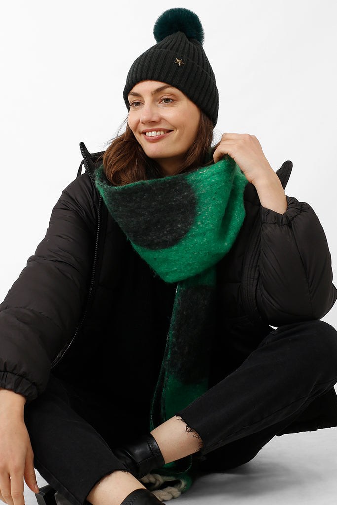 model wearing a green pom pom hat with a gold star motif