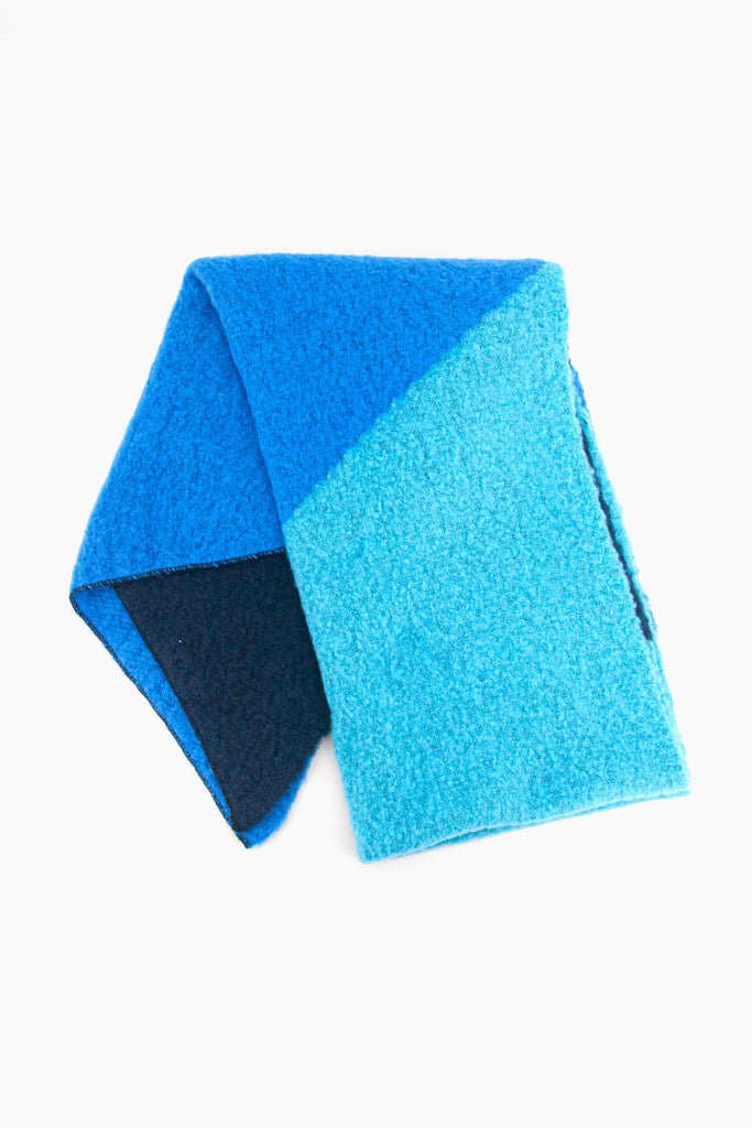 showing the asymmetric colour block scarf folder flat, showing the light blue, royal blue and navy blue tones clearly.