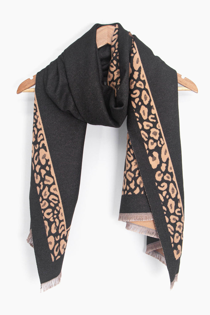 showing the black and camel leopard print border winter scarf draped around a coat hanger, showing how it would look when worn.