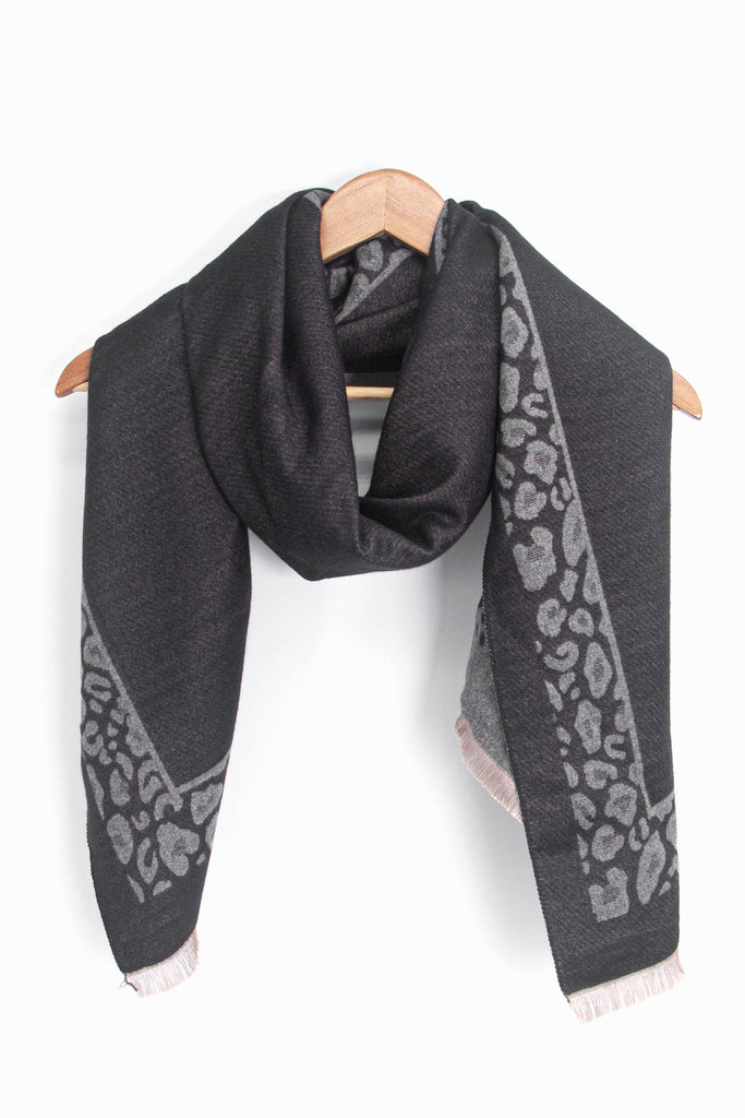 showing the black and grey leopard print border winter scarf draped around a coat hanger, showing how it would look when worn.