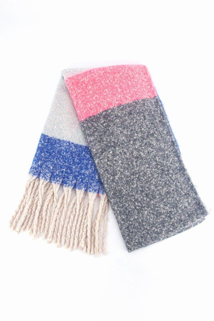 showing the scarf folded while laying flat, the pink, grey and blue colour block design is clearly shown as is the cream tasselled fringe.