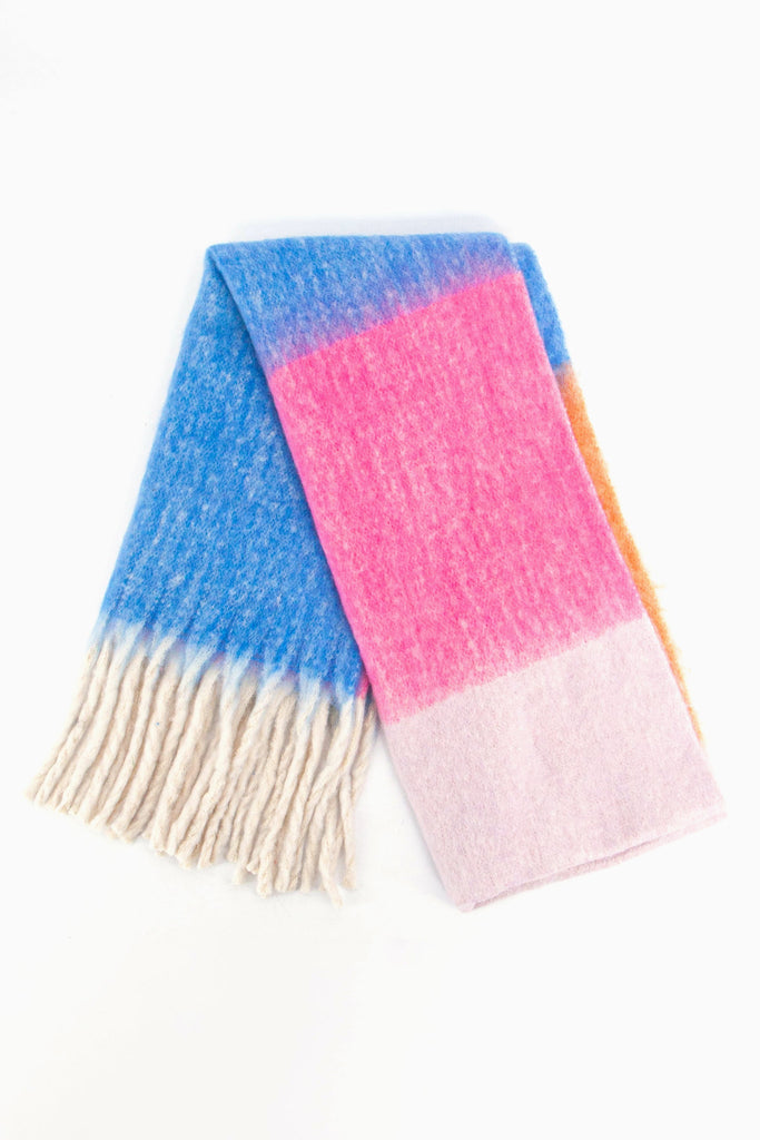 showing the scarf folded while laying flat, the pink, blue and orange colour block design is clearly shown as is the cream tasselled fringe.