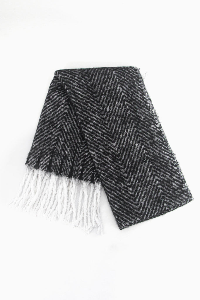 showing the scarf folded while laying flat, the black herringbone pattern is clear as is the white tassel trim.