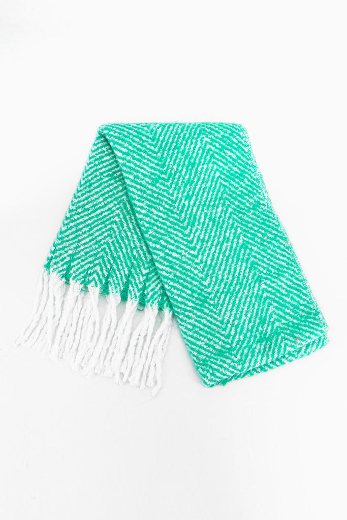 showing the scarf folded while laying flat, the green herringbone pattern is clear as is the white tassel trim.