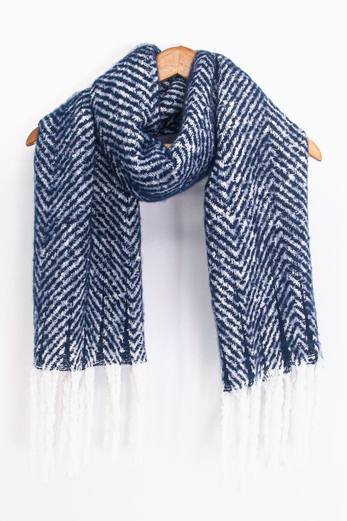 showing the navy blue and white herringbone pattern winter scarf draped around a coat hanger, showing how it would look when worn.