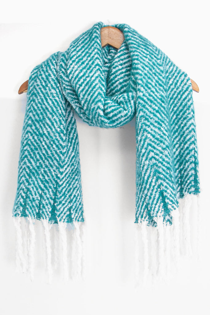 showing the turquoise and white herringbone pattern winter scarf draped around a coat hanger, showing how it would look when worn.