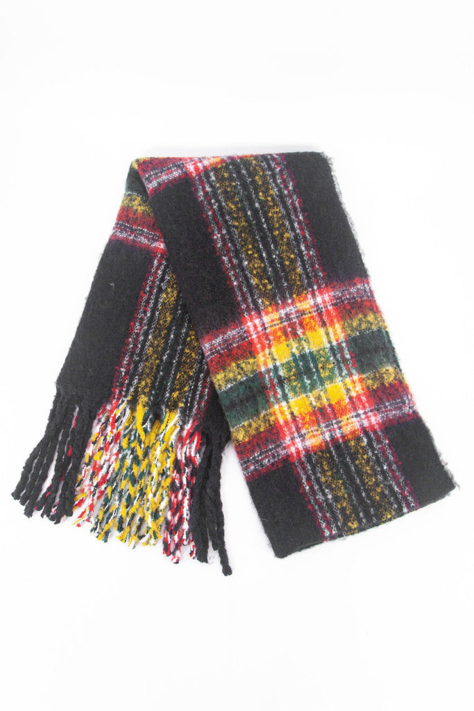 showing the scarf folded while laying flat, the black tartan checked pattern is clear as is the colourful tassel trim.