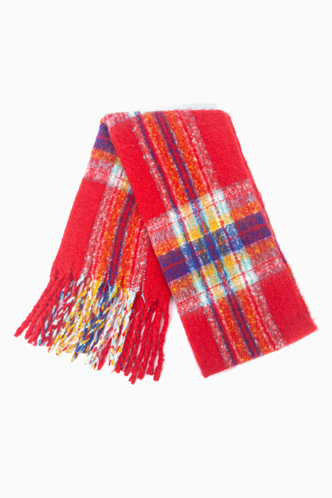 showing the scarf folded while laying flat, the red tartan checked pattern is clear as is the colourful tassel trim.