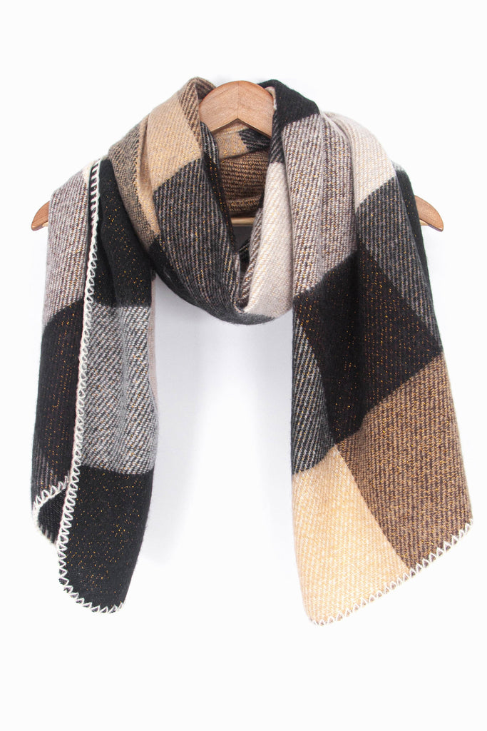showing the black and neutral square check pattern winter scarf draped around a coat hanger