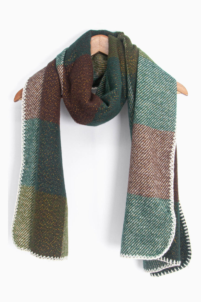 showing the green and brown square check pattern winter scarf draped around a coat hanger