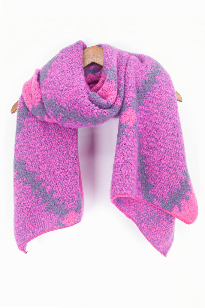 showing the fuchsia pink cross hatch pattern winter scarf draped around a coat hanger, showing how it would look when worn.