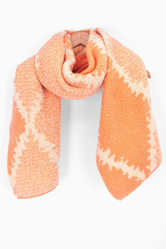 showing the orange cross hatch pattern winter scarf draped around a coat hanger, showing how it would look when worn.