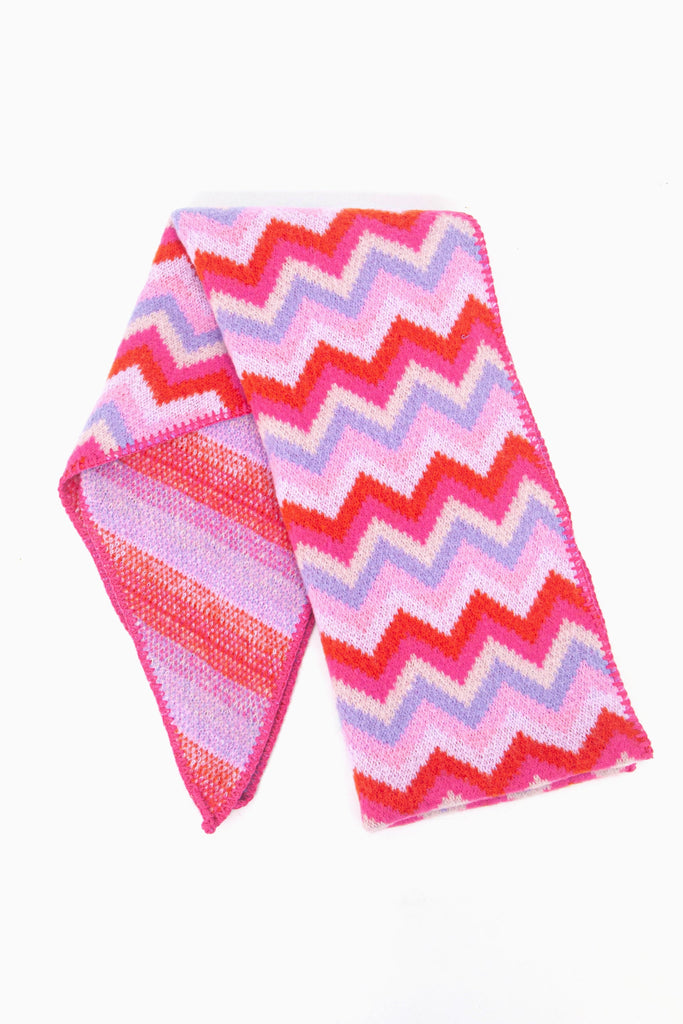 showing the scarf folded while laying flat, the multicoloured pink and lilac zig zag pattern is clearly highlighted.