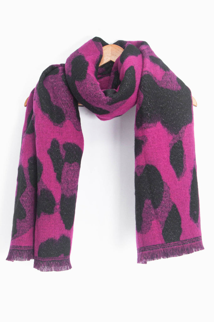 showing the fuchsia pink animal print glitter winter scarf draped around a coat hanger, showing how it would look when worn.