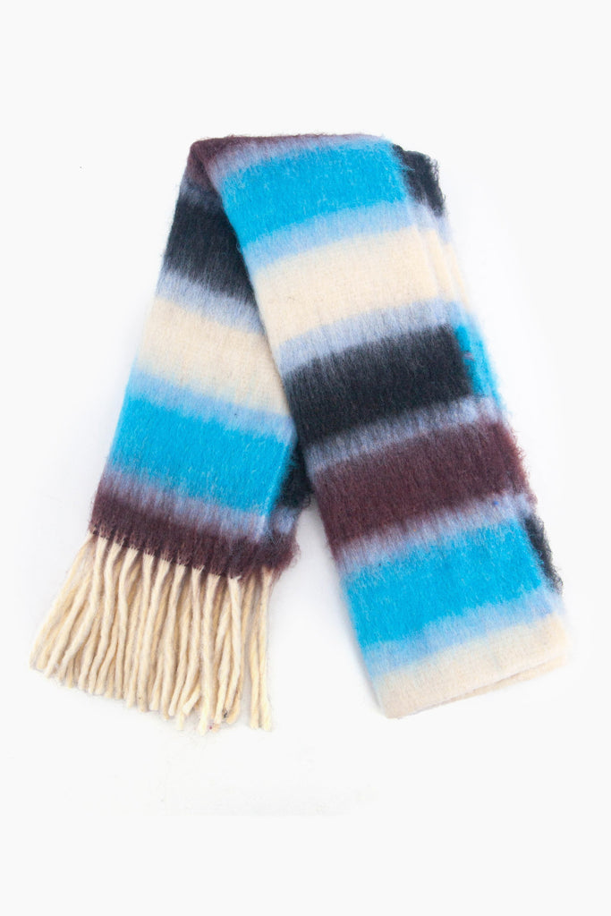 showing the scarf folded while laying flat, the blue, black and white striped pattern is highlighted as is the cream tassel fringe