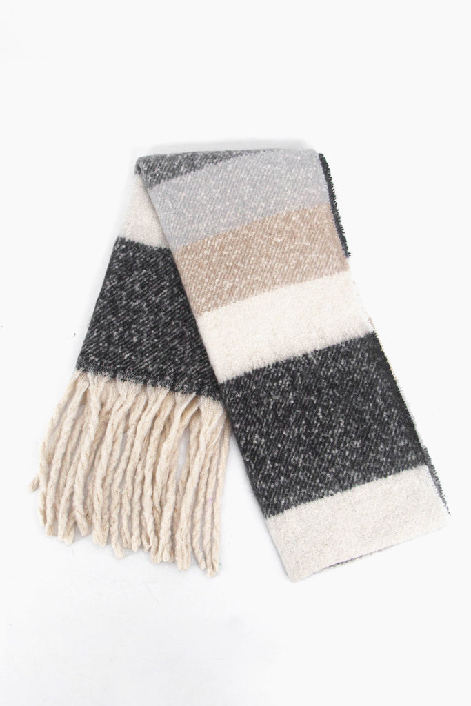 showing the scarf folded while laying flat, the grey, white and beige striped pattern is highlighted as is the cream tassel fringe