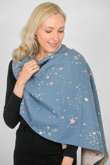 model wearing a denim blue winter scarf with an all over scattered star print pattern in pink and grey
