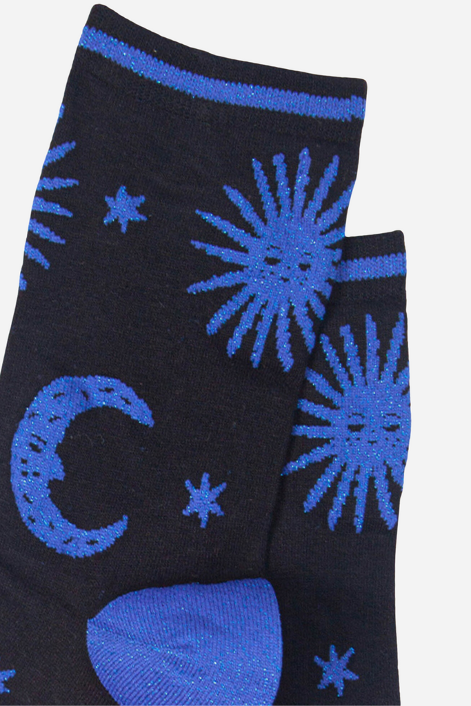 close up of the blue glitter sun and moon pattern on the black bamboo socks