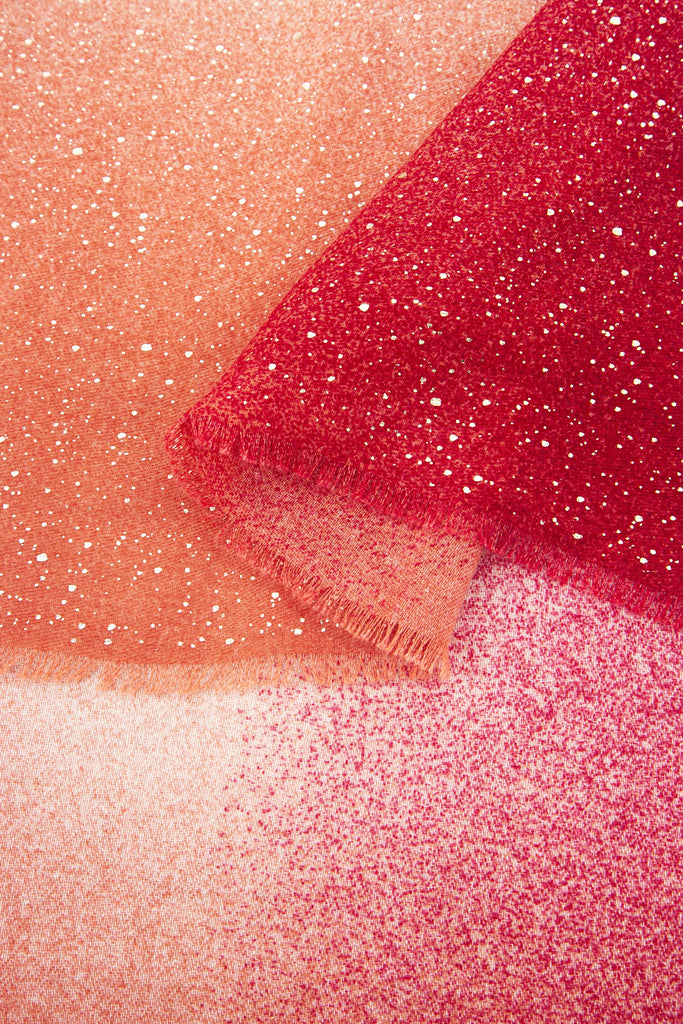 close up of the soft viscose fabric, the red ombre and foil speckles are clearly visible.