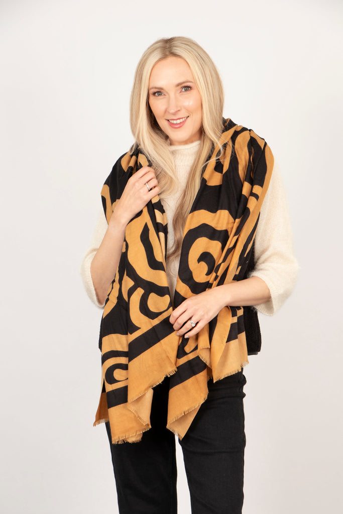 model wearing a black and neutral camel scarf with a swirling pattern.