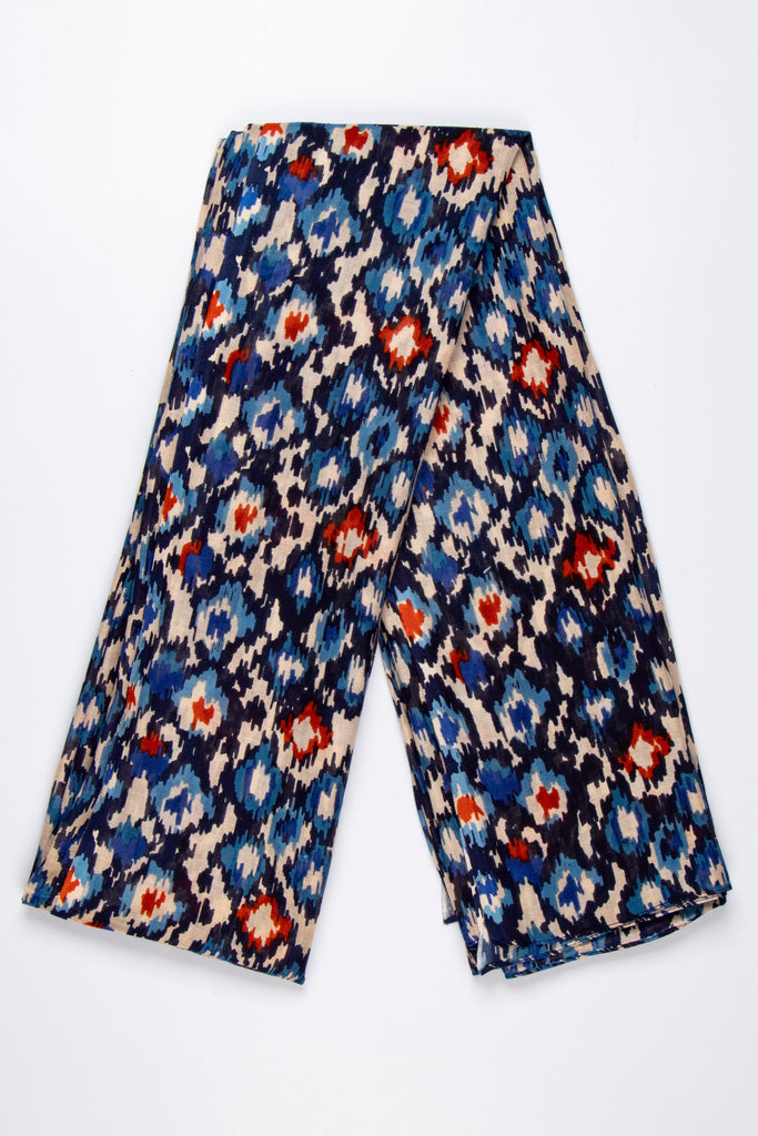 showing the scarf folded, the abstract spot pattern is shown all over the design. the base of the scarf is beige with black, with blue and orange spots and pattern all over