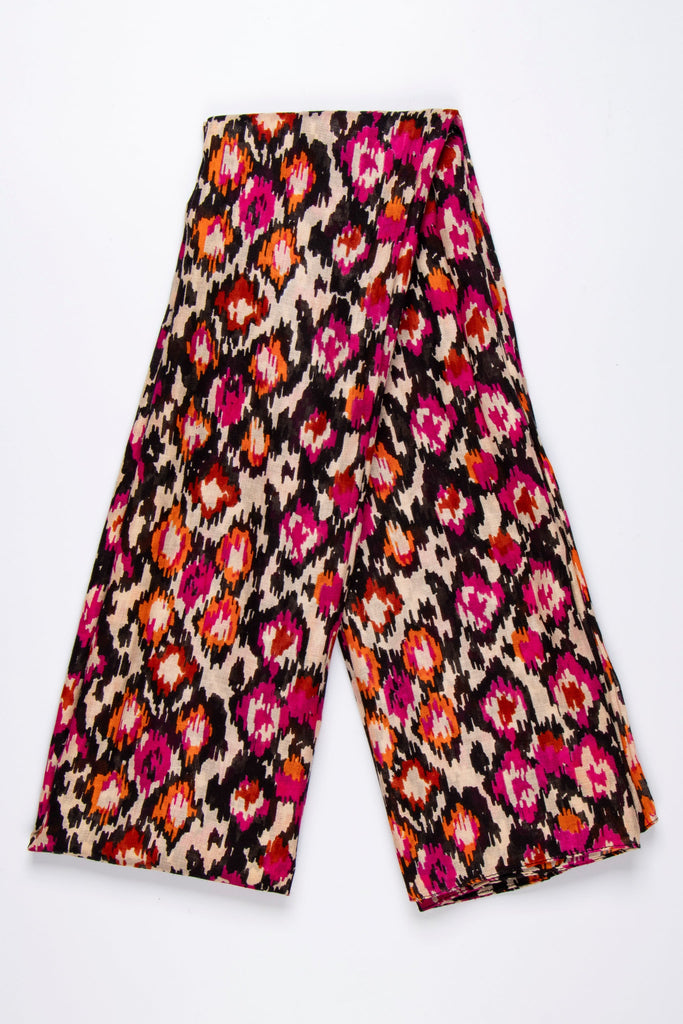 showing the scarf folded, the abstract spot pattern is shown all over the design. the base of the scarf is beige with black, pink and orange spots and pattern all over