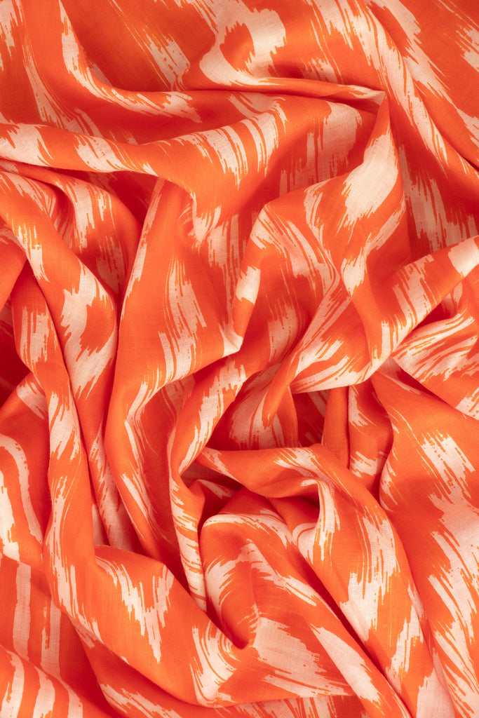 close up image of the lightweight cotton fabric and vibrant orange aztec pattern