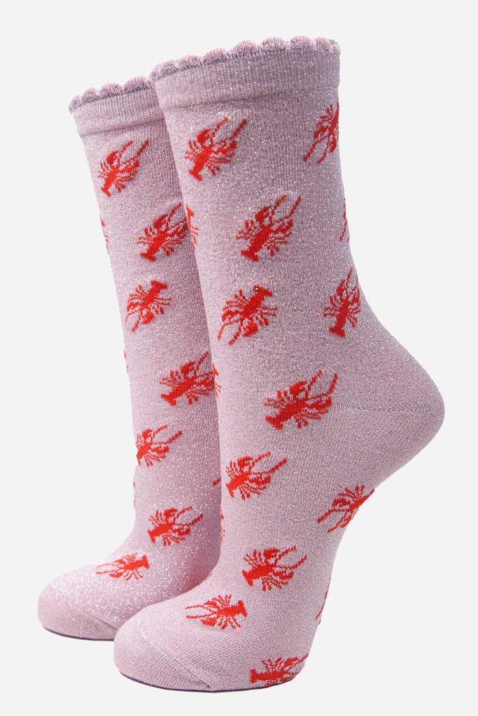 light pink socks with a red lobster parttern and an all over silver glitter sparkle, the socks have frilly scalloped cuffs
