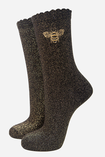 black socks with an embroidered gold bee on the ankle, the socks have a scalloped cuff and an all over glitter sparkle