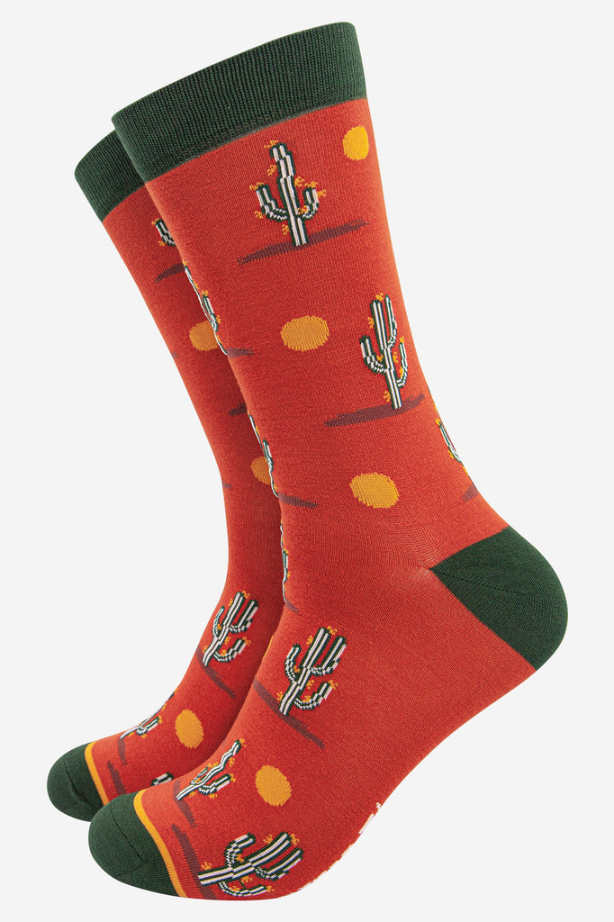 orange bamboo socks with green heel, toe and cuff with a pattern of cacti and suns looking like a wild west desert scene