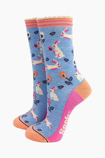 light blue bamboo socks with a pattern of white rabbits and orange and pink flowers. the socks have an orange and pink striped cuff.