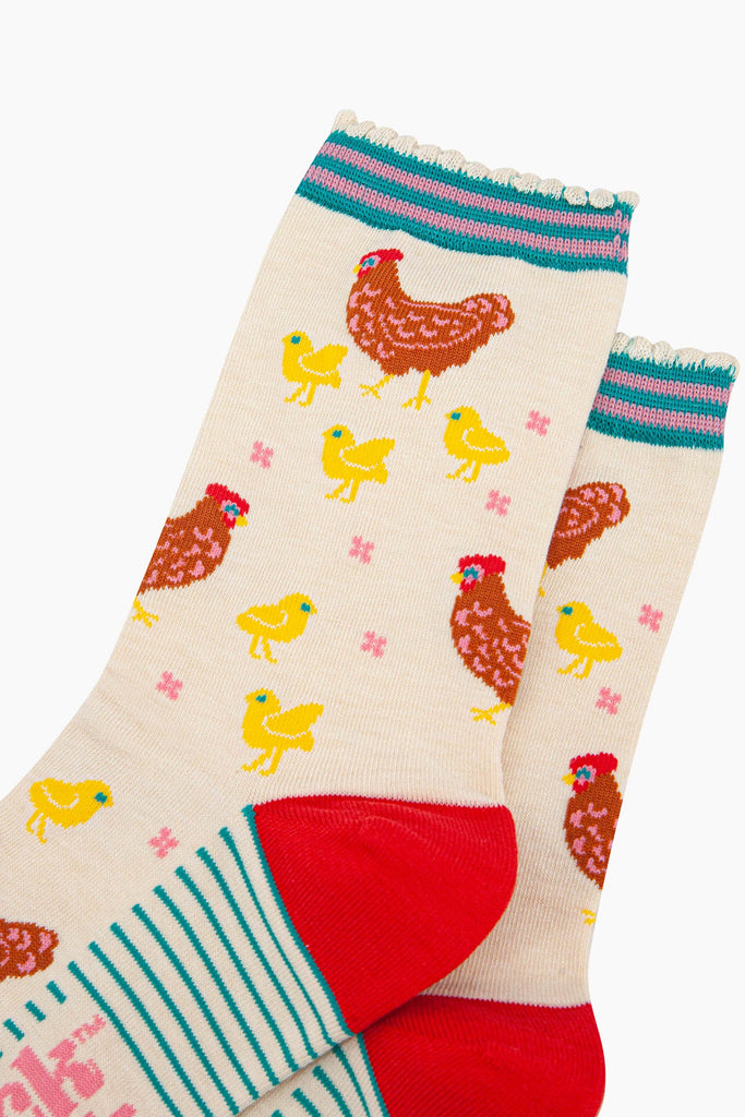 close up of the pattern. the mother hens are brown and are surrounded by small yellow baby chicks. there are small pink flowers scattered around the design. 