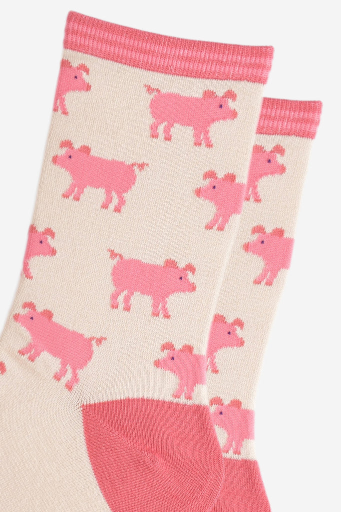 close up of the pink pig pattern on the cream bamboo socks, the pigs have curly tails and floppy ears