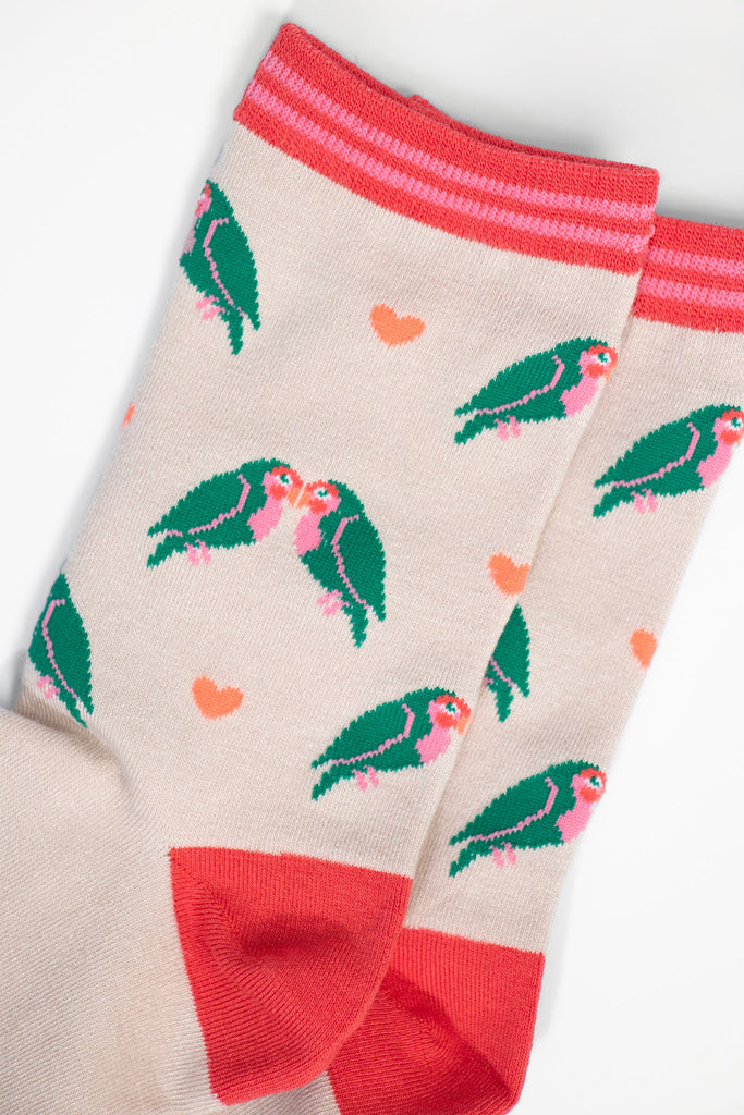 close up of the love bird and heart pattern, the love birds are green with pink bellies and beaks, they are in pairs and leaning in together like they are kissing. the love hearts are a pale peach pink colour