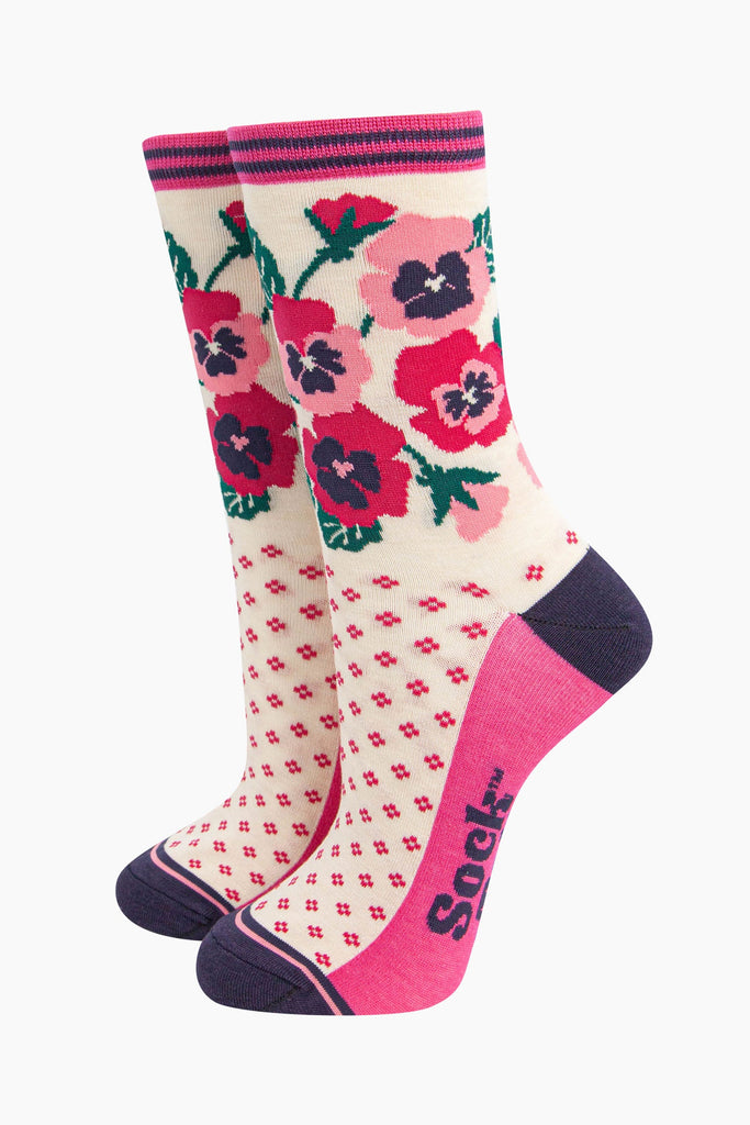 cream bamboo socks with a navy blue heel and toe and fuchsia pink sole. the ankle of the socks is covered with a fuchsia pink and light pink pansy flower arrangement. 