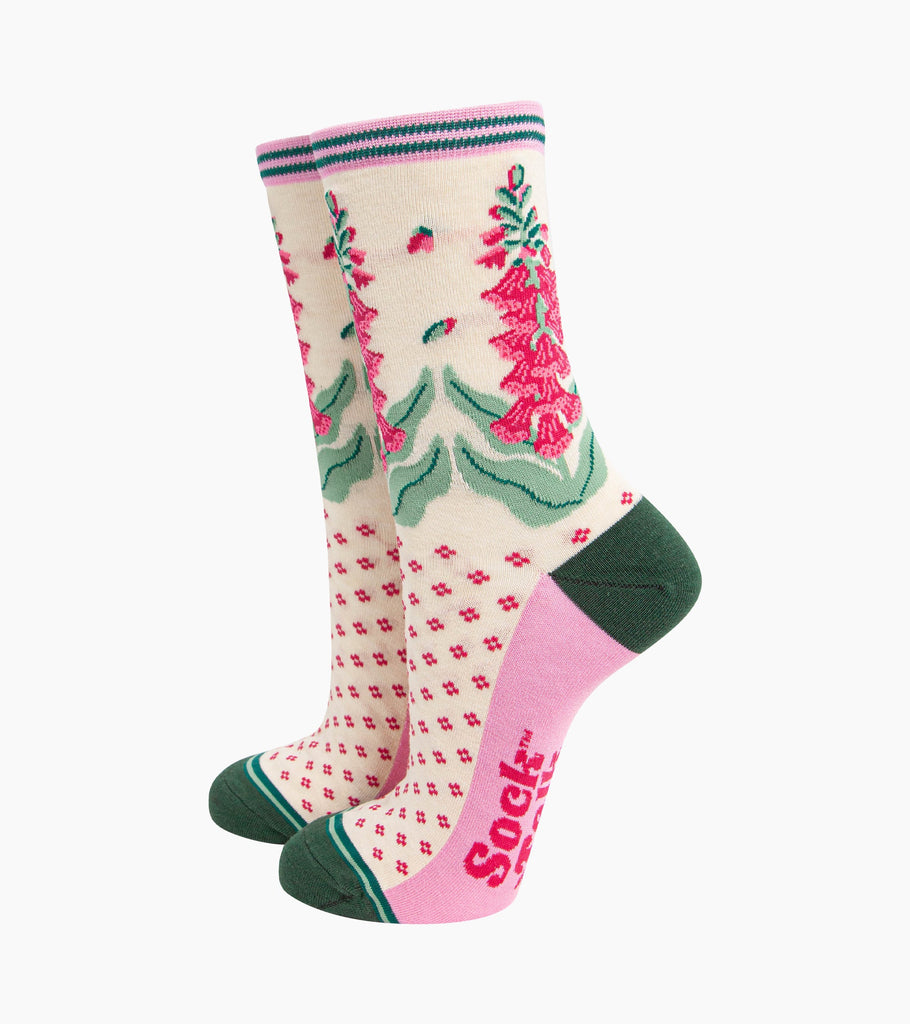cream bamboo socks with a dark green heel and toe and light pink sole. the ankle of the socks is covered with fuchsia pink and green foxgloves.