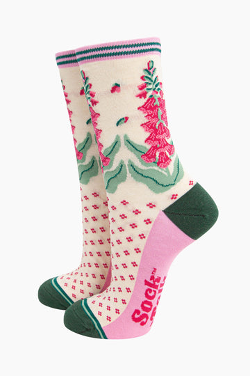 cream bamboo socks with a dark green heel and toe and light pink sole. the ankle of the socks is covered with fuchsia pink and green foxgloves.