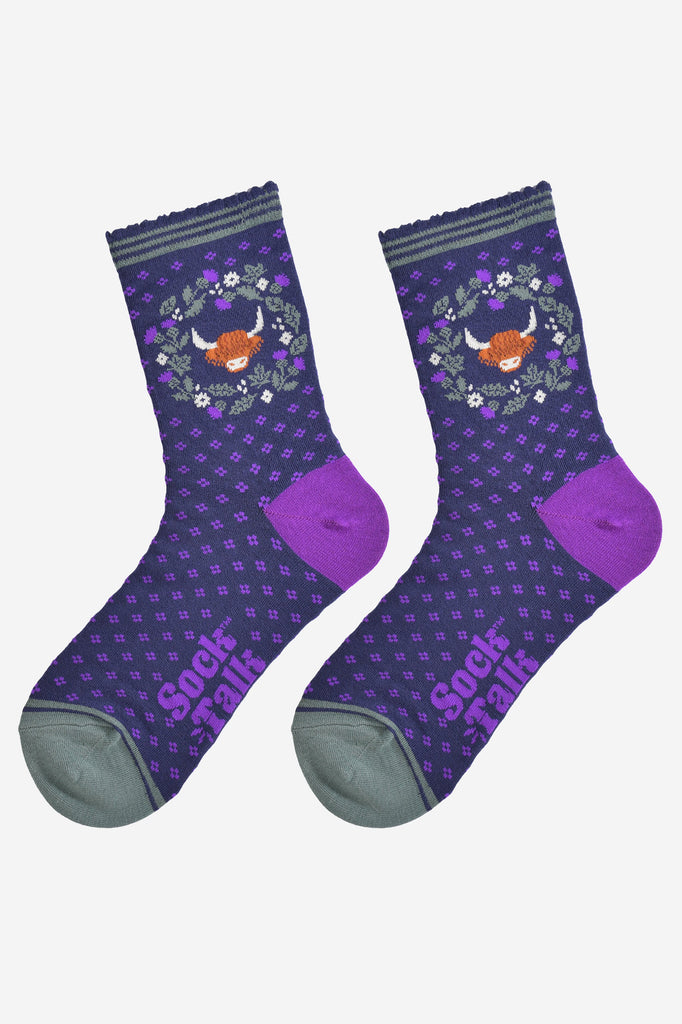 highland cow and wreath bamboo socks laying flat, showing the all over purple spotted pattern, green and purple thistle flower wreath and highland cow
