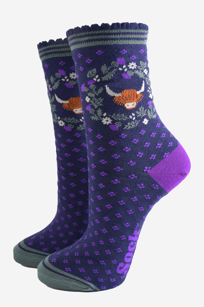 navy blue and purple ankle socks with scalloped cuffs featuring a highland cow and a wreath featuring purple and green scottish thistle flowers