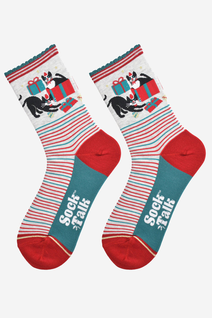 showing the socks laying flat, the black and white cats playing with christmas presents are prominent on the ankles and contrast the green and red striped patten on the feet of the socks