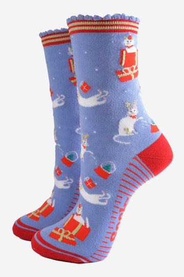 light blue socks with a contrasting red heel, toe and striped cuff and sole with a pattern of white cats playing with snow globes and christmas presents