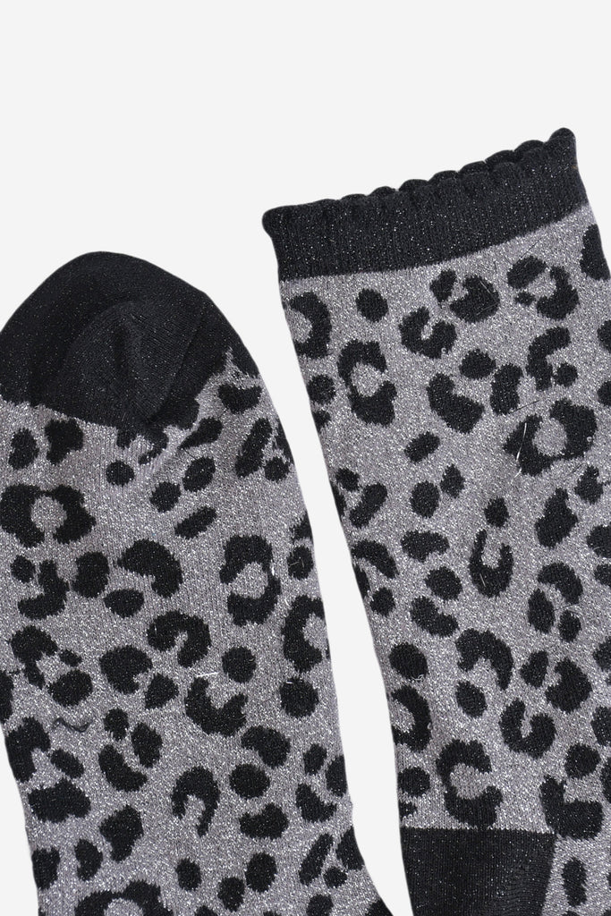 showing the toe and cuff of the socks, the toe is black and sparkly like the black leopard print pattern, the cuff is also black and sparkly and has a scalloped edge
