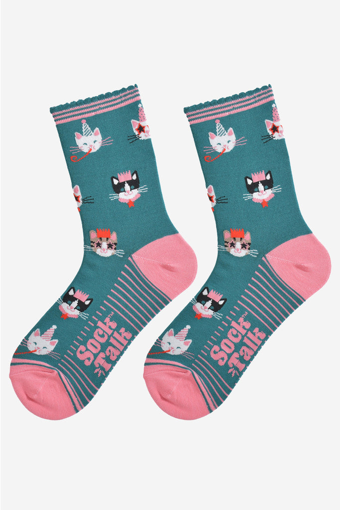showing the green party cat socks laying flat, the sole has pink stripes and the cat face pattern is all over the socks.